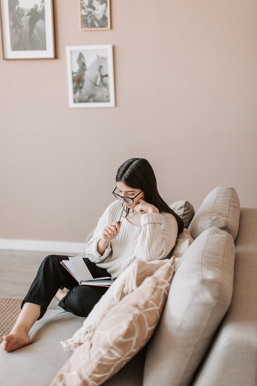 thoughtful young female freelancer reading diary at home