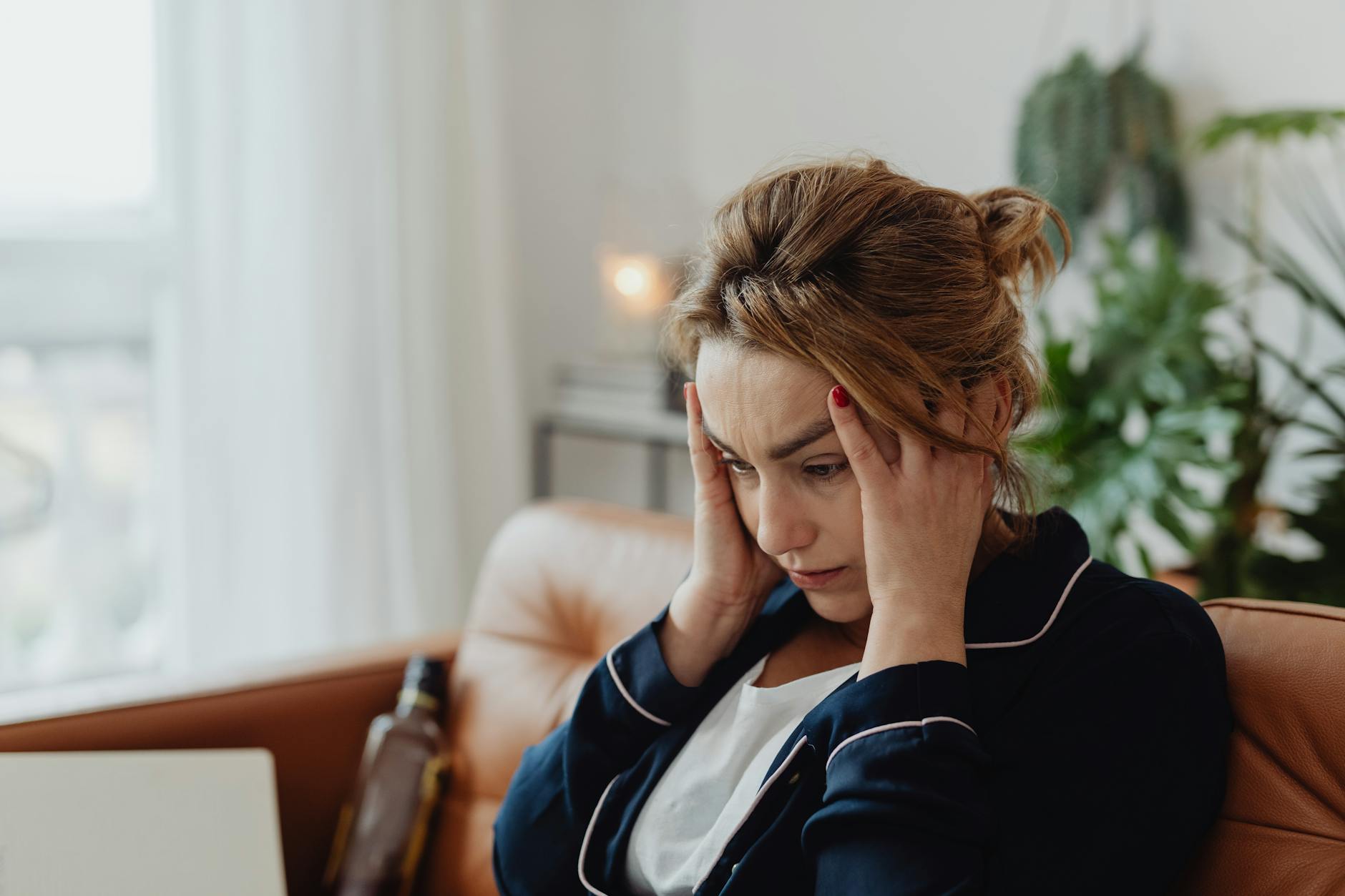 woman wearing a pajama holding her head